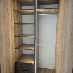 AR-GRA WYKOŃCZENIA WNĘTRZ ARKADIUSZ GRABOWSKI - Otwarta szafa wnękowa z oświetleniem LED, półkami z forniru imitującego drewno i szufladą na dole.