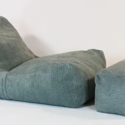 Turkusowy fotel puf z podnóżkiem, wykonany z prążkowanego materiału, na białym tle.