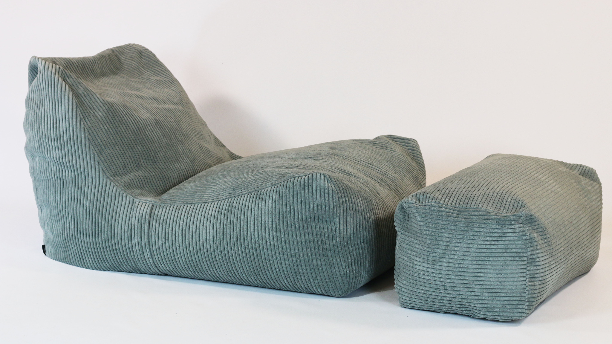 Turkusowy fotel puf z podnóżkiem, wykonany z prążkowanego materiału, na białym tle.