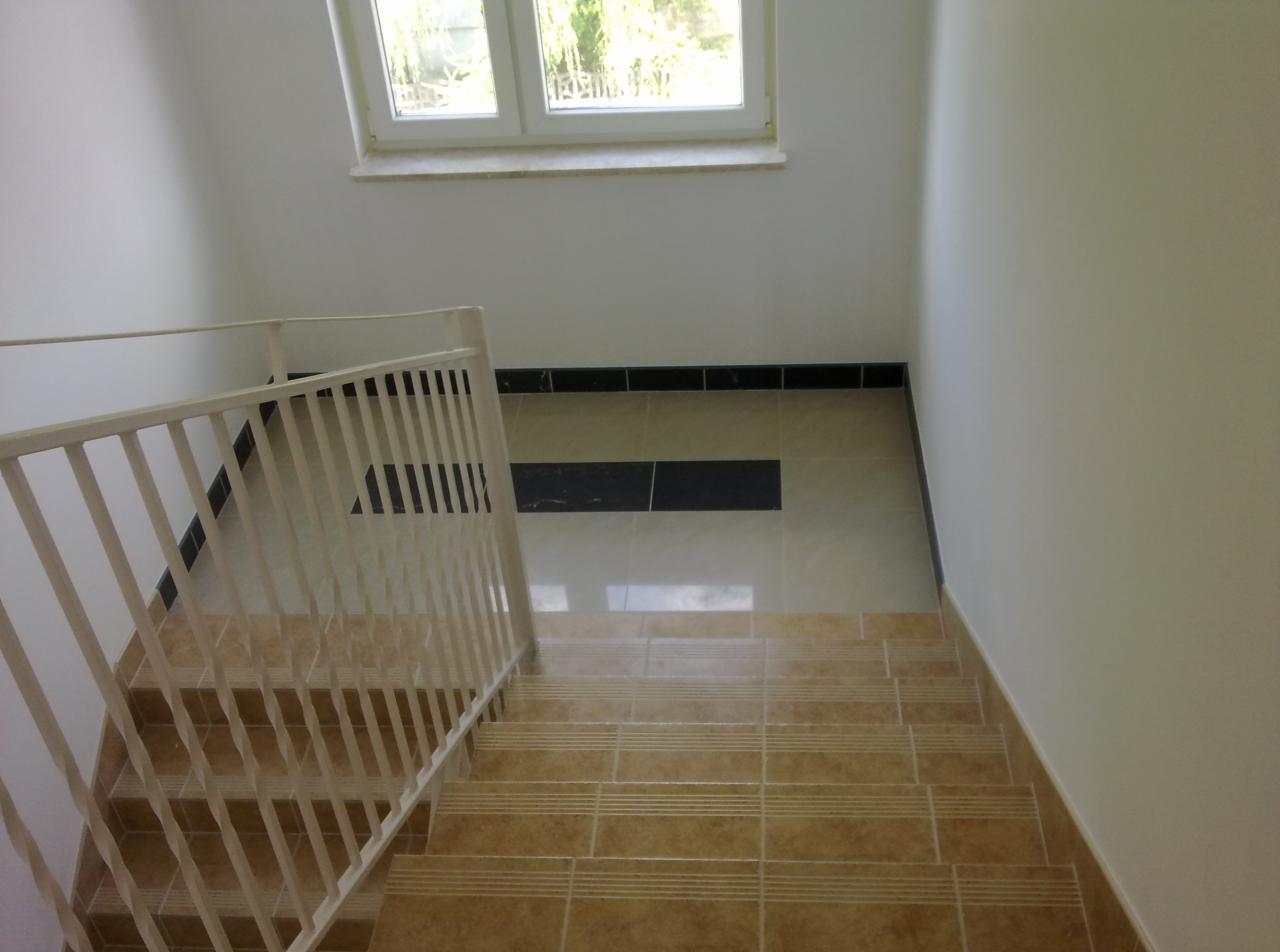 Schody wyłożone brązowymi płytkami z białymi fugami, biała balustrada, widok z góry, Pułtusk.