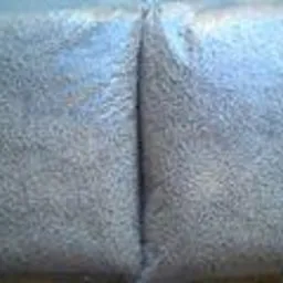 Dwa przezroczyste worki wypełnione jasnymi, drobnymi granulkami pelletu drzewnego, ułożone obok siebie na płaskiej powierzchni.