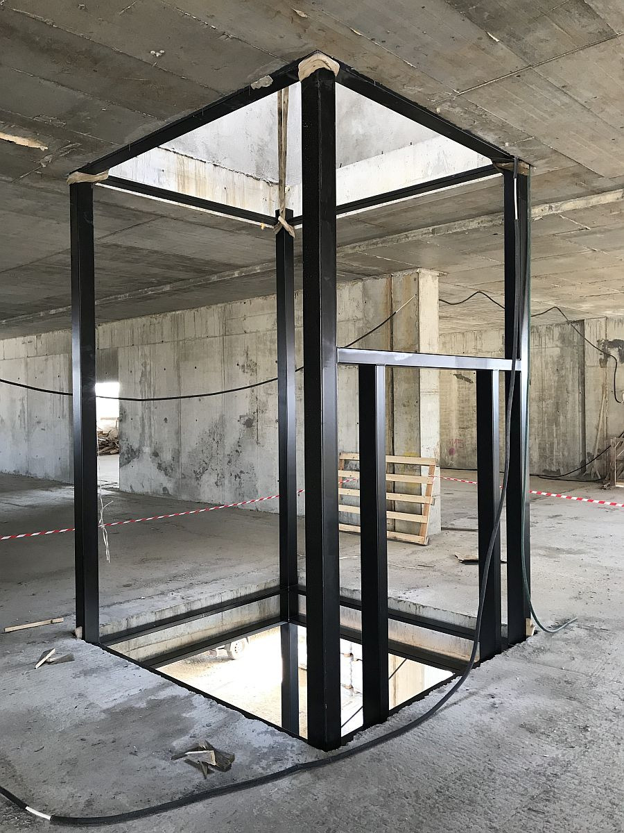 Wykonywanie konstrukcji stalowej w surowym stanie, czarne profile tworzące ramę otworu w stropie, widoczne elementy zabezpieczające narożniki.