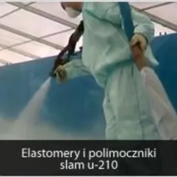 Pracownik w kombinezonie ochronnym natryskuje pianę izolacyjną na powierzchnię, widoczny wąż i dysza aplikacyjna, w tle konstrukcja dachu hali.