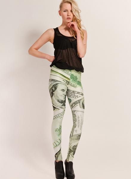 Modelka w Warszawie prezentuje legginsy z nadrukiem banknotów, czarny top i czarne botki na obcasie na białym tle.