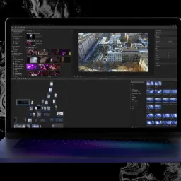 Laptop z otwartym programem do edycji wideo, wyświetlającym oś czasu projektu, podgląd ujęcia z budynkami w tle i panel efektów, na tle abstrakcyjnego wzoru.