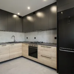 Nowoczesna kuchnia z drewnianymi szafkami dolnymi i grafitowymi szafkami górnymi, czarnym blatem, płytą grzewczą i lodówką LG, oświetlona punktowymi lampami.