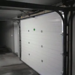 Biała segmentowa brama garażowa, widok od wewnątrz garażu. Metalowa konstrukcja prowadnic, poziome panele bramy z delikatnymi przetłoczeniami.