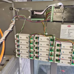 Otwarta skrzynka z elektroniką domofonową RENZ: moduły przyciskowe, okablowanie i płyta sterująca. Widoczne oznaczenia i numery seryjne komponentów.