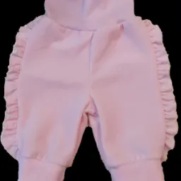 Różowe, welurowe spodnie dziecięce z wysokim stanem i falbankami po bokach, na czarnym tle.