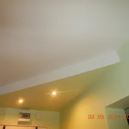 Wykończony sufit podwieszany z płyt kartonowo-gipsowych z wbudowanym oświetleniem punktowym, jasne ściany w odcieniach zieleni i żółci, widoczna instalacja elektryczna.