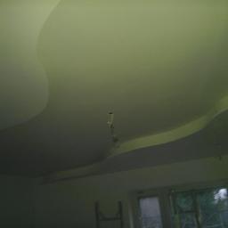 Darpol - Falisty, podwieszany sufit z płyt kartonowo-gipsowych, oświetlenie punktowe, widok z dołu, okno w tle. Nowoczesny design wnętrza.