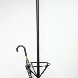 Stojak na ubrania i parasole w kolorze czarnym, wykonany z metalu, z parasolem w kwiaty. Dekoracyjny detal w domu w Brzegu. Minimalistyczny design.