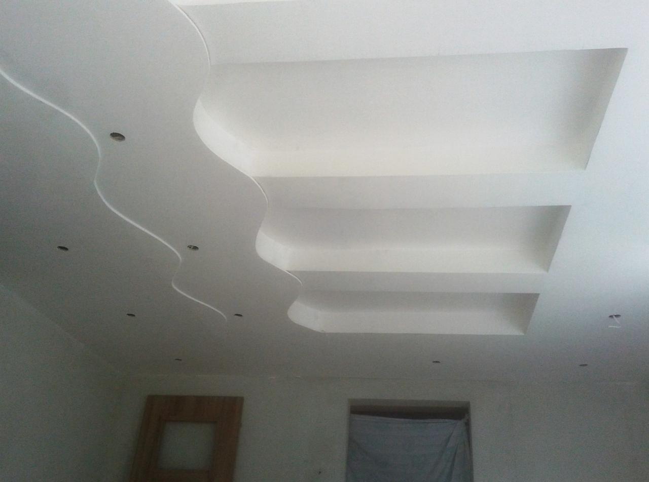 Dekoracyjny sufit z płyt kartonowo-gipsowych z falistymi elementami i wnękami, oświetlenie punktowe