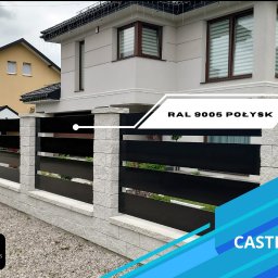 EURO-FENCES Slawomir Sulkowski - Nowoczesne ogrodzenie panelowe z czarnymi, poziomymi przęsłami i kamiennymi słupkami, RAL 9005 połysk, widok na dom w tle.