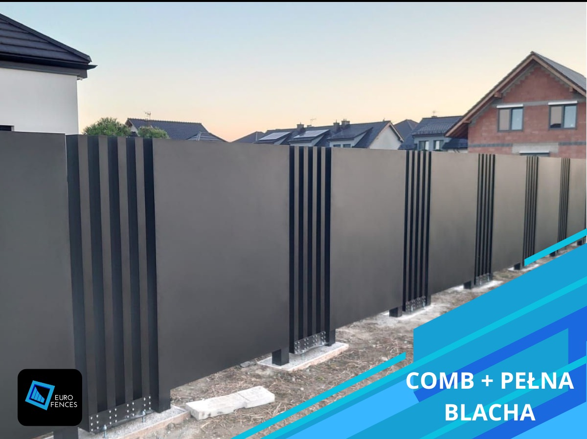 Nowoczesne ogrodzenie panelowe z pełnej blachy z elementami dekoracyjnymi w postaci wąskich pionowych listew, widoczne elementy montażowe do podłoża, w tle zabudowa jednorodzinna.