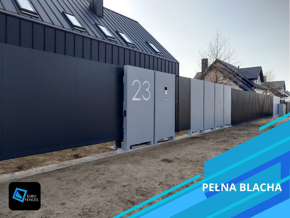 Nowoczesne ogrodzenie posesji z przesuwną bramą w kolorze grafitu i szarości z numerem domu 23, na tle domu z czarnym dachem. Pełna blacha.
