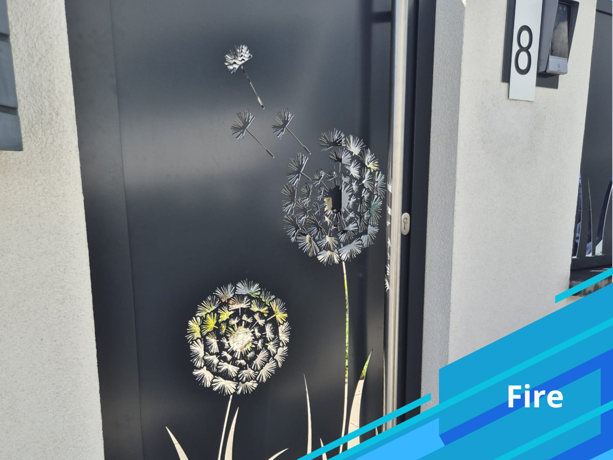 Nowoczesne, antracytowe drzwi wejściowe z dekoracyjnym motywem dmuchawca, numer domu '8' widoczny z boku.