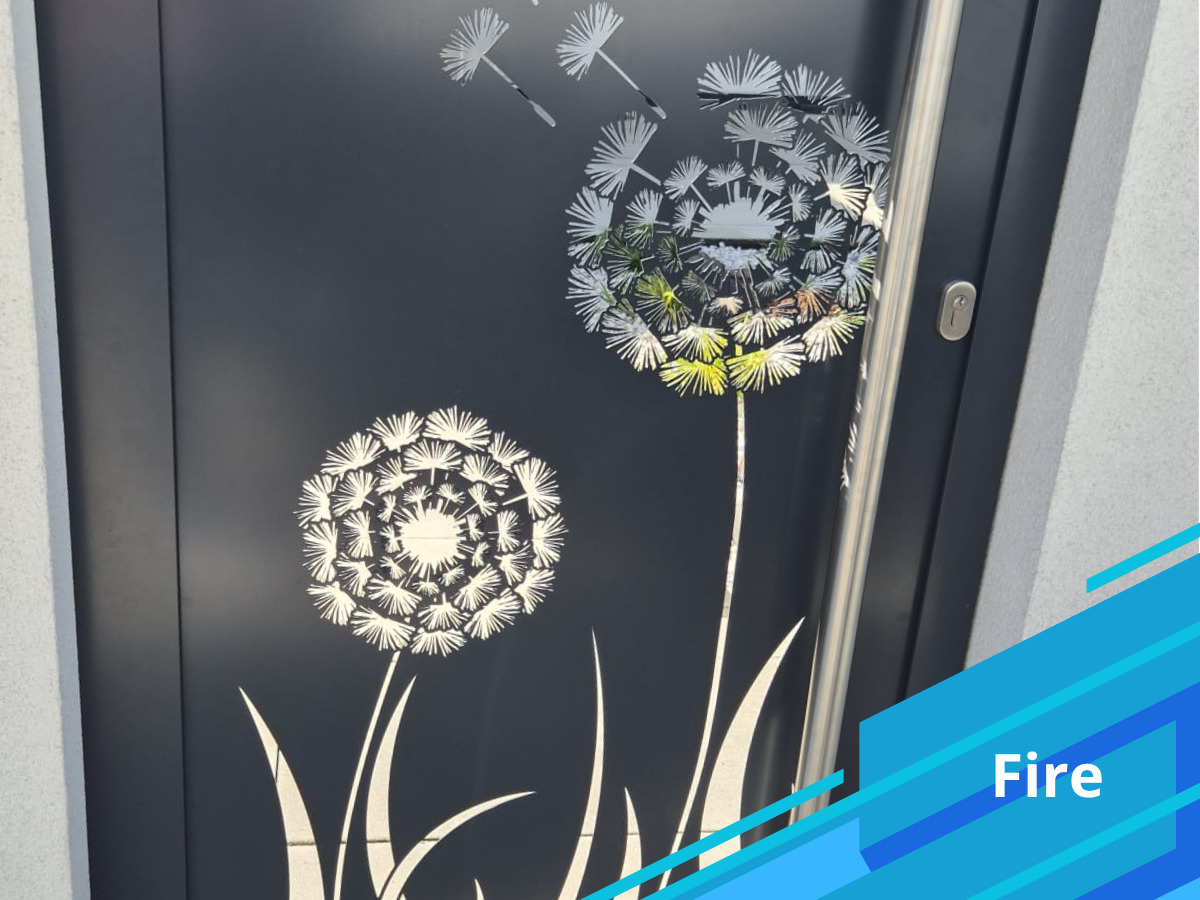 Nowoczesna, grafitowa brama wejściowa z dekoracyjnym motywem dmuchawca i srebrnym uchwytem, widziana pod kątem.