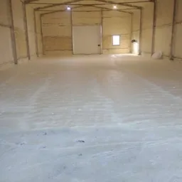 Wnętrze hali magazynowej po aplikacji izolacji natryskowej na ściany, sufit i podłogę. Widoczne ślady po pracy na podłożu.