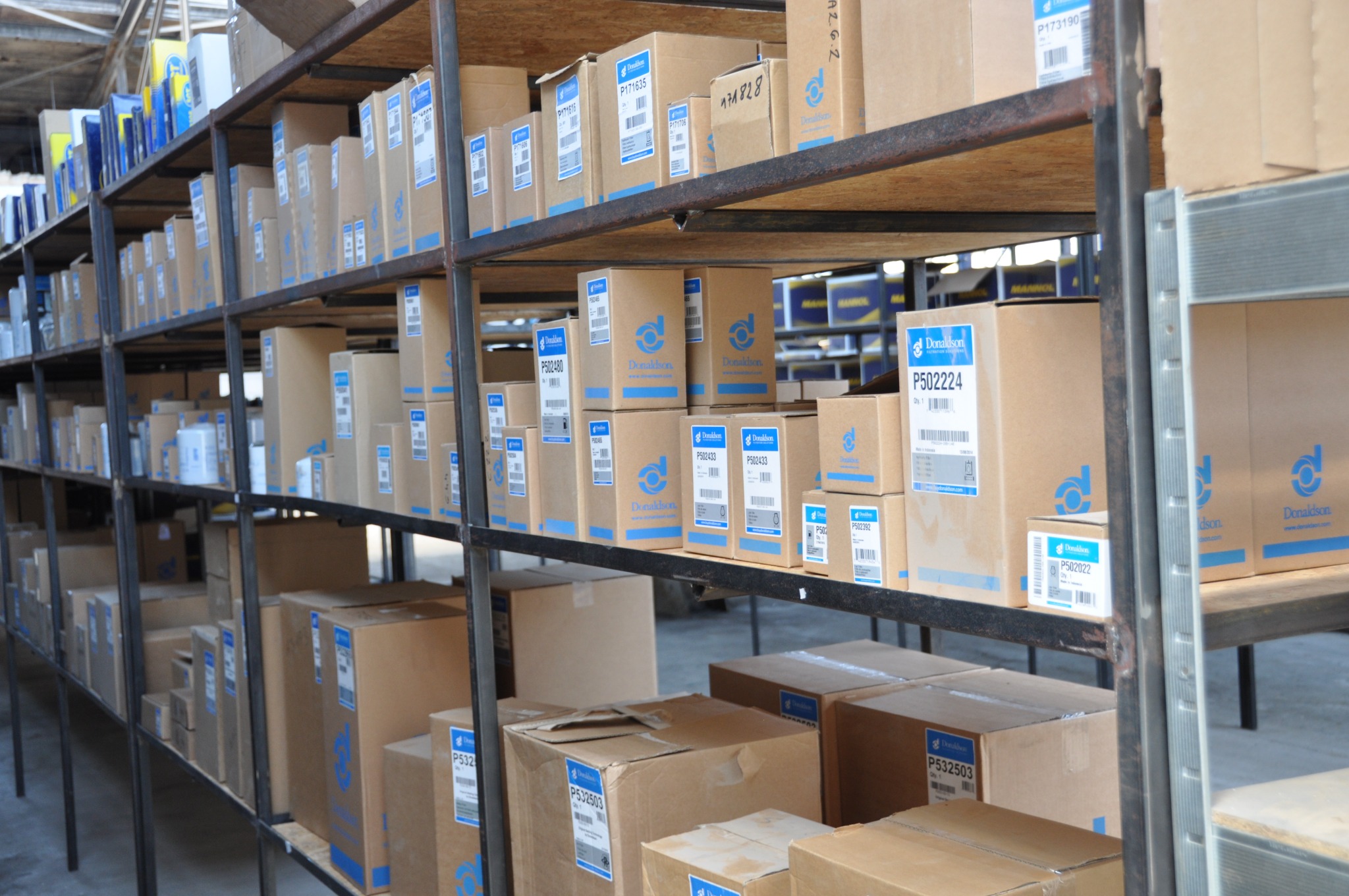 Magazynowe półki z kartonami filtrów marki Donaldson, widoczne różne modele i numery części.
