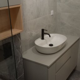 Nowy Wymiar Mebli - Nowoczesna łazienka w szarościach z owalną umywalką nablatową i czarną armaturą, widoczne niedokończone podłączenie elektryczne na ścianie