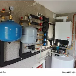 Nowoczesna instalacja grzewcza z piecem gazowym i zbiornikami w Wołominie. Widoczne rury, zawory i manometry. Estetyczne i funkcjonalne rozwiązanie.