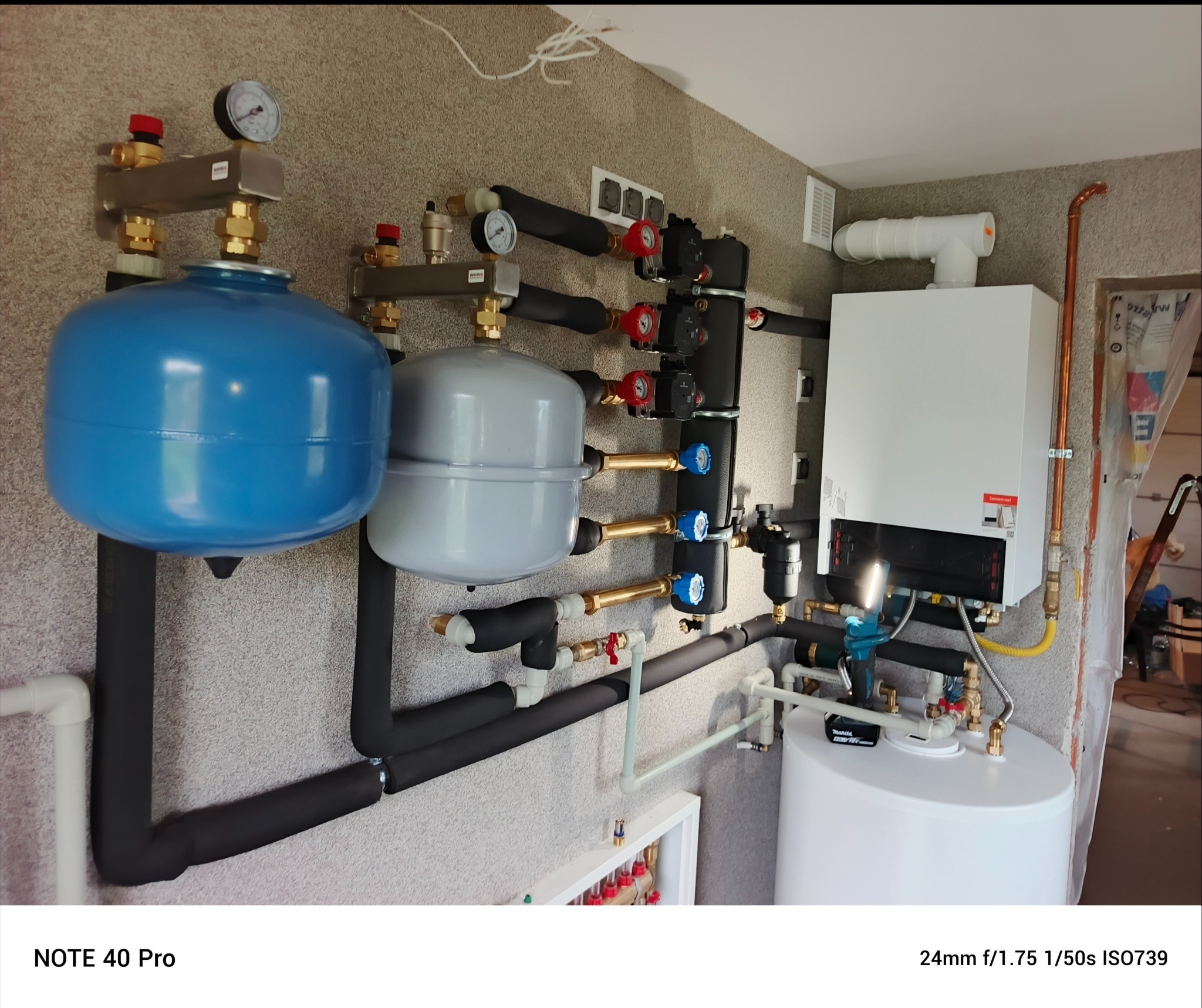 Nowoczesna instalacja grzewcza z piecem gazowym i zbiornikami w Wołominie. Widoczne rury, zawory i manometry. Estetyczne i funkcjonalne rozwiązanie.