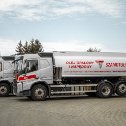 MAC-BENZ MACIEJ I BARBARA KŁACZKIEWICZ SPÓŁKA JAWNA - Cysterny firmy MAC-BENZ z napisem 'OLEJ OPAŁOWY I NAPĘDOWY' stojące w rzędzie na placu, widok z boku na pierwszą cysternę, w tle drzewa iglaste i pochmurne niebo.