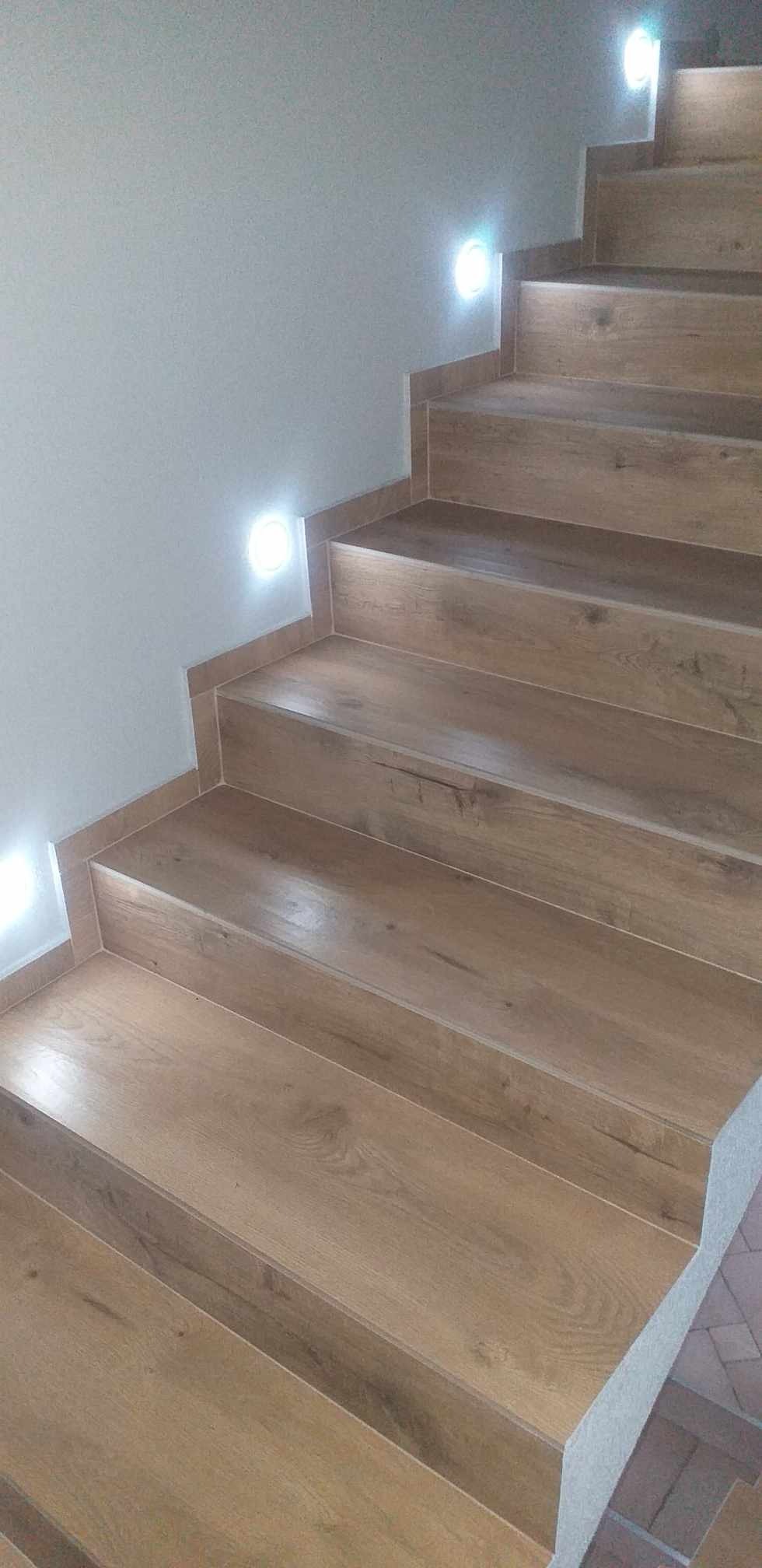 Schody wykończone panelami imitującymi drewno, z oświetleniem punktowym w ścianie, widok z dołu.