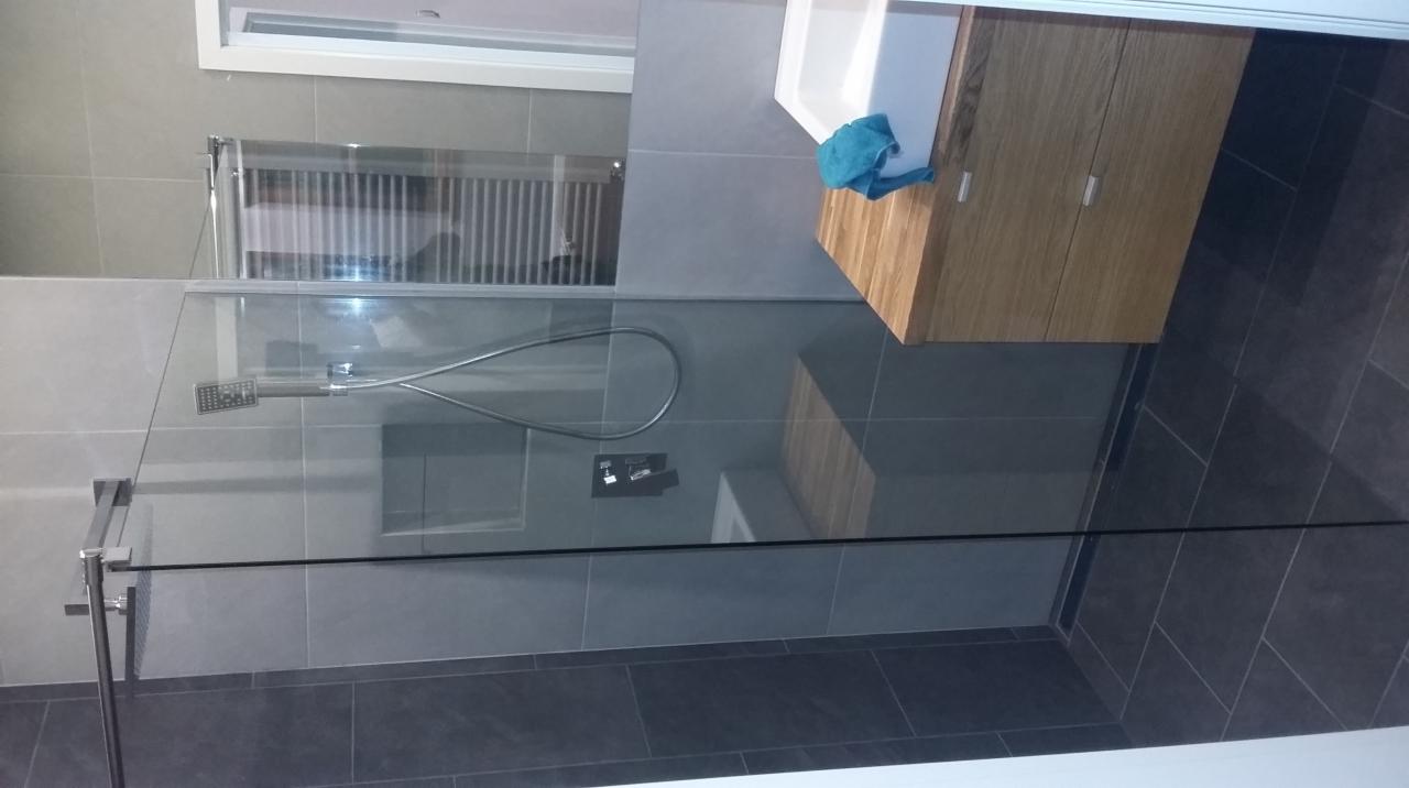 Nowoczesna łazienka z kabiną prysznicową ze szkła, szarą glazurą i drewnianą szafką pod umywalką. Minimalistyczny design,  bateria podtynkowa.