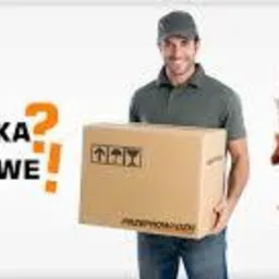 Uśmiechnięty mężczyzna w czapce trzyma karton z symbolami ostrożnego transportu, w tle kobieta relaksuje się w fotelu, a obok napis 'Przeprowadzka z nami to łatwe!'