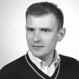 Portret biznesowy mężczyzny w swetrze i koszuli, czarno-biały, na jasnym tle. Zdjęcie doradcy finansowego z Łodzi.