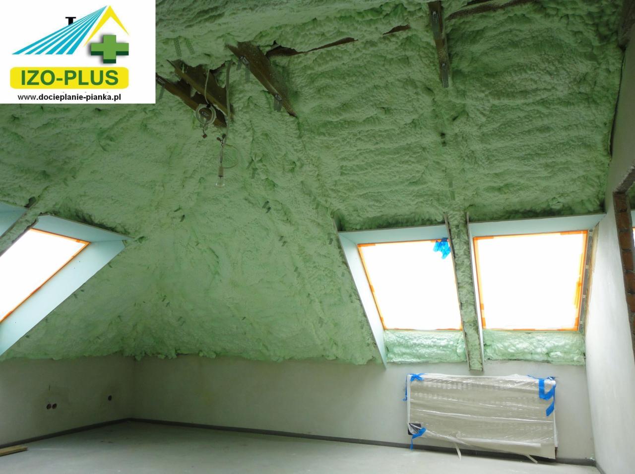Poddasze ocieplone pianką PUR: widoczne okna dachowe i grzejnik zabezpieczony folią. Ściany i sufit pokryte jednolitą warstwą pianki, tworząc izolację termiczną.