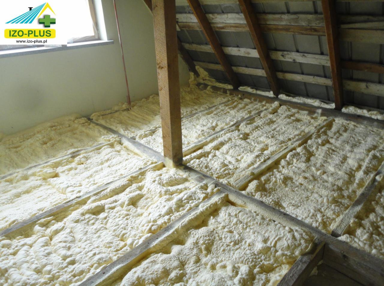 Poddasze z drewnianą konstrukcją wypełnione pianką PUR, widoczne belki stropowe i okno w tle. Izolacja wykonana starannie, pianka równomiernie rozprowadzona.