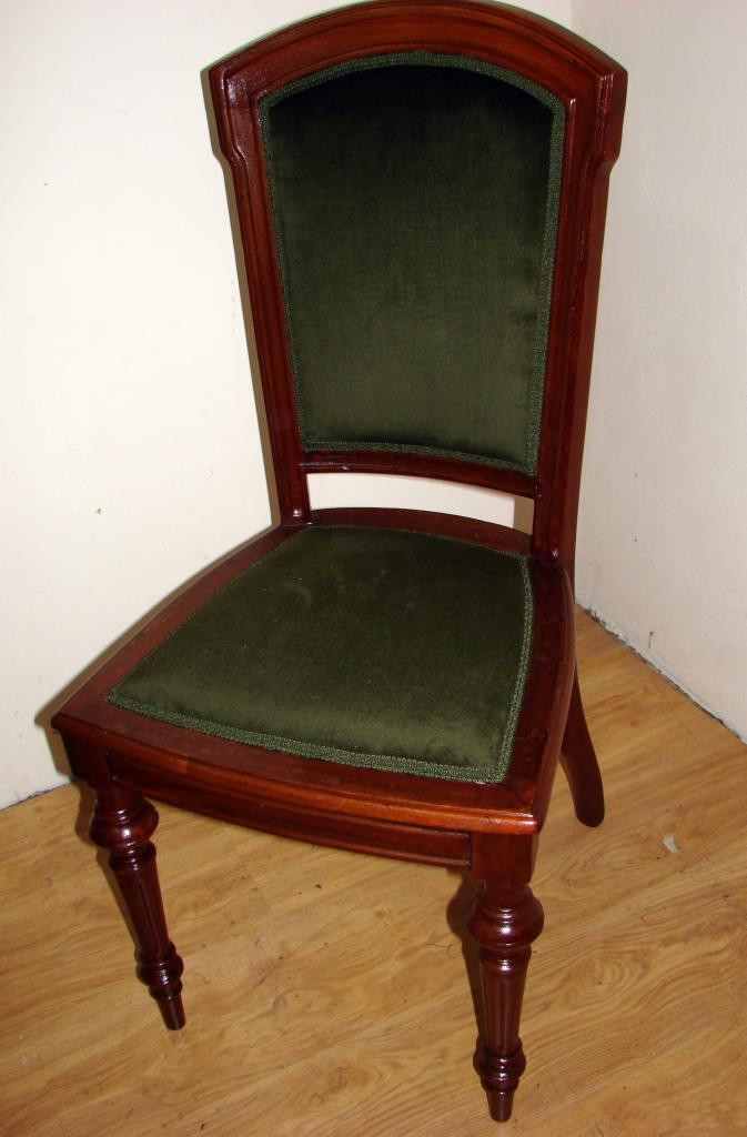 Drewniane krzesło po renowacji z ciemnozieloną tapicerką, widoczne detale wykończenia i toczone nogi.