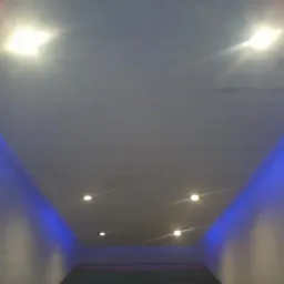 Nowoczesny sufit podwieszany z oświetleniem LED w kolorze niebieskim i punktowymi lampami halogenowymi, widok z dołu.