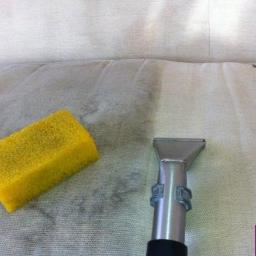 TECTUS Agnieszka Jaworska - Czyszczenie tapicerki sofy jasnym odkurzaczem piorącym, obok leży żółta gąbka, widoczne ślady po czyszczeniu.