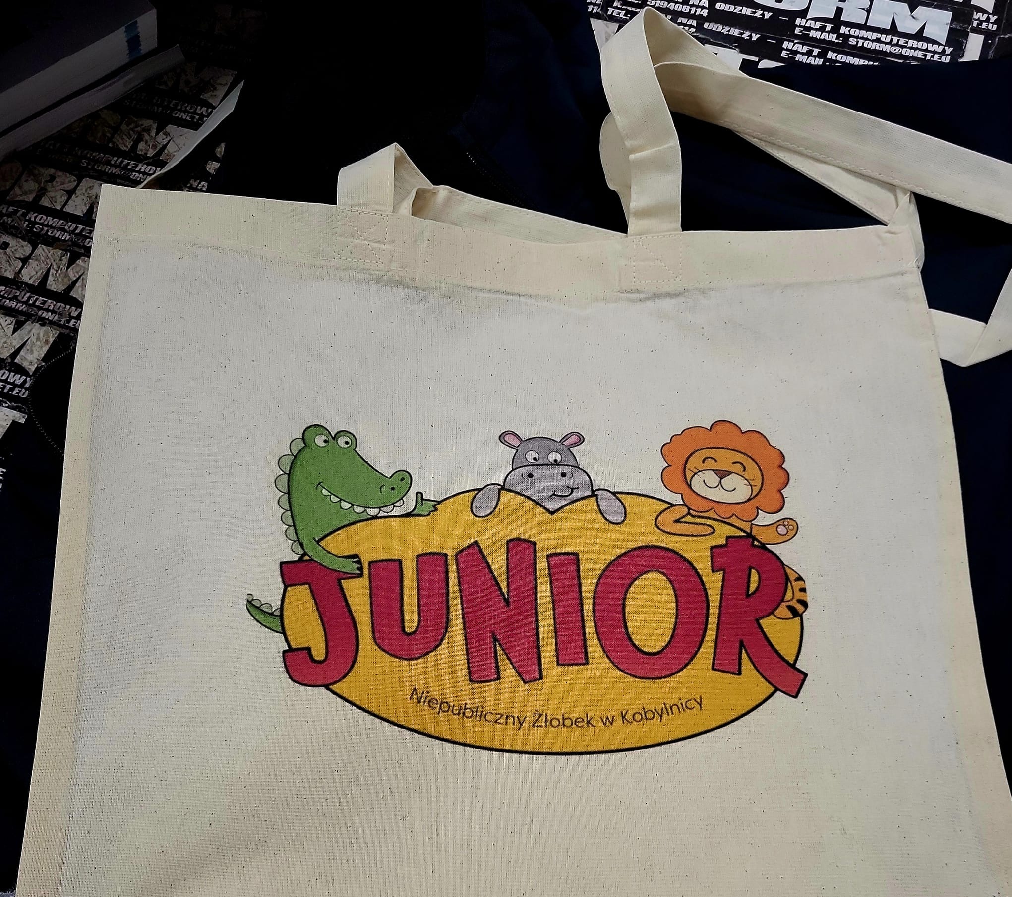 Eko torba z nadrukiem logo 'Junior Niepubliczny Żłobek w Kobylnicy' oraz wizerunkami krokodyla, hipopotama i lwa.
