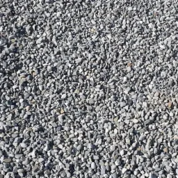 Drobne, szare kamienie o zaokrąglonych krawędziach, tworzące jednolitą powierzchnię pod jasnym, naturalnym oświetleniem.