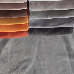 LULU JUSTYNA KIEDROWSKA - Próbki materiałów welurowych w odcieniach beżu, brązu, pomarańczy i szarości, ułożone warstwami, prezentują bogatą paletę barw i faktur tkanin.