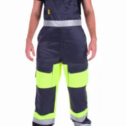 Mężczyzna prezentuje szare ogrodniczki z neonowożółtymi wstawkami i odblaskowymi pasami, stojąc na białym tle.