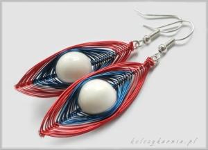 Ręcznie robione kolczyki z drutu w kolorach czerwonym, białym i niebieskim, o kształcie wydłużonej łezki z białą perłą w centrum, zawieszone na srebrnych biglach.