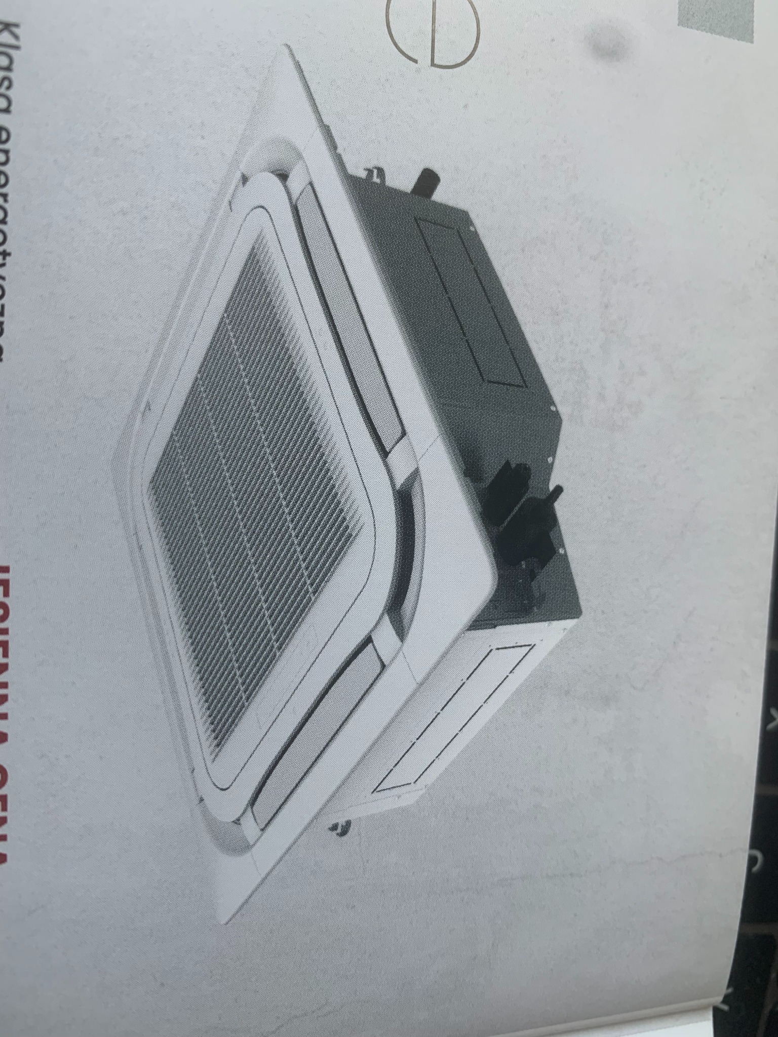 Klimatyzator kasetonowy sufitowy, widok z boku, z widoczną kratką wentylacyjną i obudową w kolorze białym, na tle białej ściany.