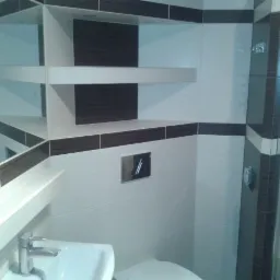 Biało-brązowa łazienka po remoncie: płytki, umywalka, lustro i kabina prysznicowa. Nowoczesny design z geometrycznym wzorem płytek i minimalistyczną armaturą.