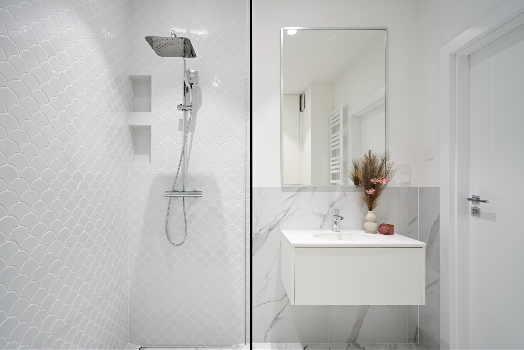 Nowoczesna łazienka z kabiną prysznicową wykończoną białą mozaiką w kształcie rybiej łuski i umywalką nablatową na tle marmurowej ściany. Minimalistyczny design.