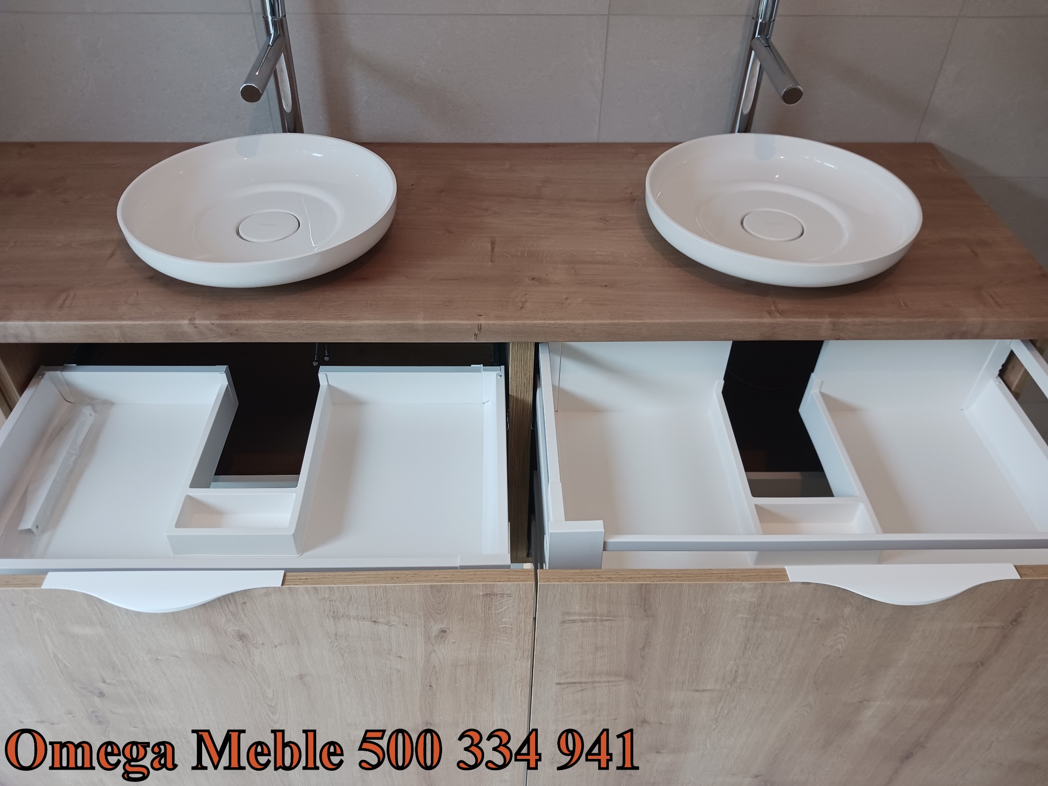 Łazienkowa szafka pod umywalkę z dwoma okrągłymi, białymi umywalkami nablatowymi i otwartymi szufladami z białymi organizerami, drewnopodobny fornir, minimalistyczne baterie.