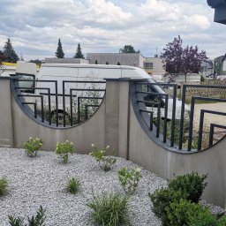 Cr-budsystem Robert Cendalski - Nowoczesne ogrodzenie betonowe z metalowymi przęsłami o półokrągłym kształcie, widok na biały samochód dostawczy za ogrodzeniem, szara nawierzchnia z kamyczków i roślinność.