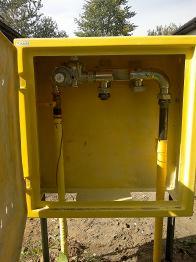 Żółta szafka gazowa z zainstalowaną armaturą w Chorzowie, widok z bliska. Element instalacji gazowej na zewnątrz budynku, złącza i rury.