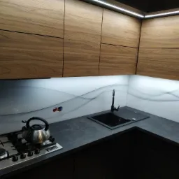 Nowoczesna kuchnia z drewnianymi szafkami górnymi, czarnym zlewem i blatem, oraz szklanym panelem ściennym z abstrakcyjnym wzorem fal.