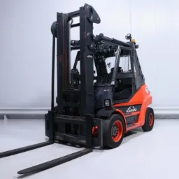 Pomarańczowo-czarny wózek widłowy Linde H70 z kabiną, widoczny od tyłu w sterylnym, białym magazynie z poziomymi panelami ściennymi.